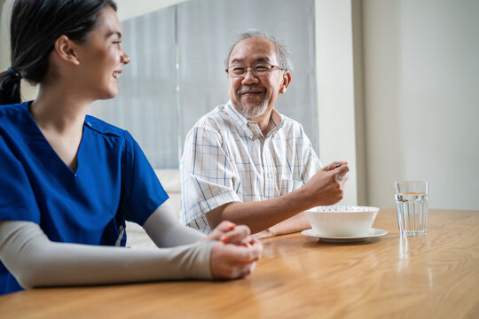 Senior older man patient eat food with Caregiver nurse at nursing home