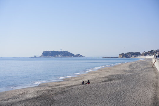 Parents and children playing on the sandy beach and Enoshima seen over the coast from Shichirigahama