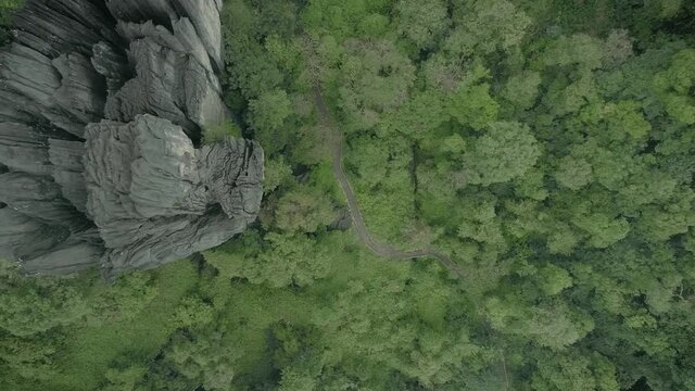 Aerial top down view of road amidst dense greenery leading to unusual rocks formation at Yana caves in Karnataka.