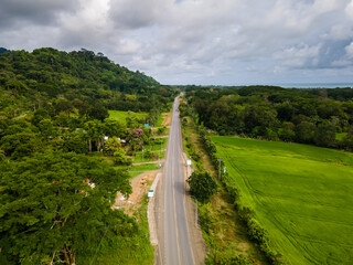 Beautiful aerial view of the Dominical Beach and a road between the beach and the green mountains in Costa Rica