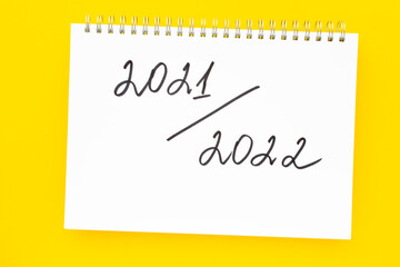 2021-2022 New academic year. Back to school concept. Handwriting inscription in white notepad, on vivid yellow background. Flat lay, top view.