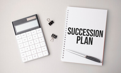 The word SUCCESSION PLAN a is written on a white background next to a pen ,calculator and reports. Business concept