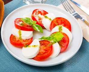 Caprese salad with fresh tomatoes, mozzarella cheese and basilic herb, dish of Italian cuisine