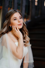 Naklejka premium beautiful and gentle bride sits on a dark wooden staircase. 