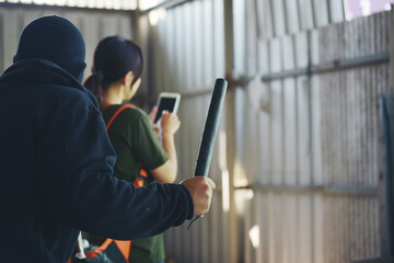 Thief armed man rob woman by baton on street stalker behind young woman back. Woman on phone careless stalker sneaking to steal, rob aggressive by danger bandit. Thief using baton nightstick weapon.