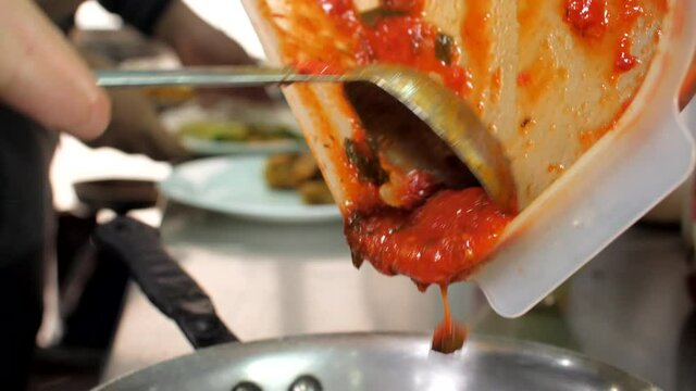 Chef preparing ravioli with sauce in restaurant, close-up, Mediterranean