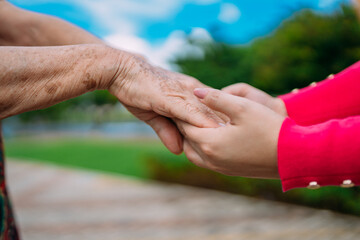 The helping hands for elderly home care in a park outdoor.