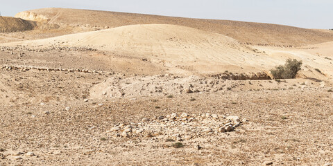 a small ancient stone circle and water channel system east of Arad in the Negev in Israel with a modern quarry in the background left