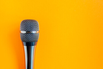 Microphone on a colorful orange background close up. Singing, writing music, karaoke online,...