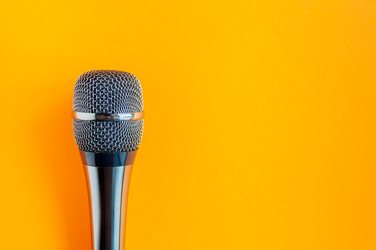 Microphone on a colorful orange background close up. Singing, writing music, karaoke online, creativity, vocals concept, symbol. Singing lessons