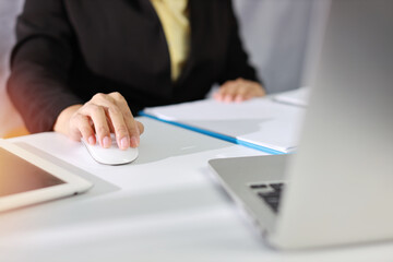 Businesswoman hands in black suit sitting and using mouse. Active woman using computer with tablet on white table with business chart and calculator in modern office with paper work