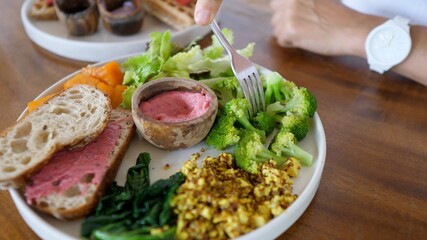 Fork dipping broccoli in a beetroot sauce. Healthy balanced nutritious vegan meals full of vegetables and plant based proteins