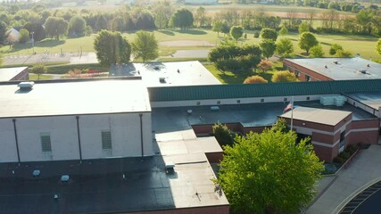 American flag at school building in USA. Educational system in America. Aerial reveal pullback shot.