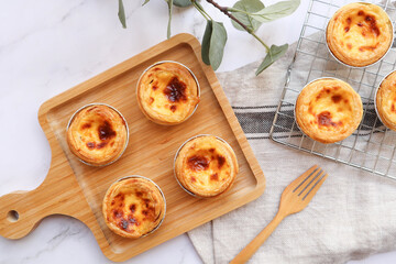 Egg tart, Portugal egg tart served on the wooden tray and cooling rack of marble table - Flat lay food
