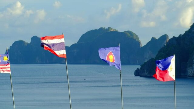 The blowing flags of ASEAN community - Thailand, Malaysia, and the Republic of Philippines  -Fluttering freely in sea background, mountains, and blue sky. And beautiful scenery of the island.