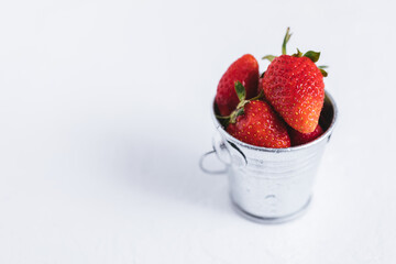 Fresh strawberries in metal cup on a white background isolated