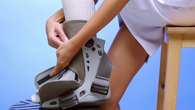 A nurse shows how to put on a leg and ankle, air-boost support splint - blue background