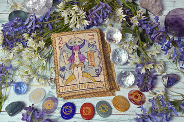 Still life with High Priestess card of the old tarot deck on witch altar table with chakra crystals...