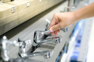 Male hand choosing stainless steel water tap in furniture store. Home improvement for domestic kitchen.