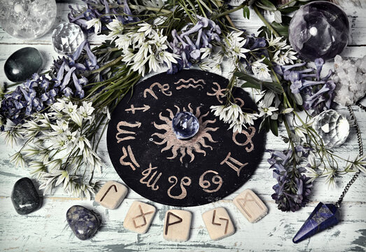 Still life with zodiac circle, runes, crystal and flowers on witch altar table. Esoteric, gothic and occult background, Halloween mystic and wicca concept.