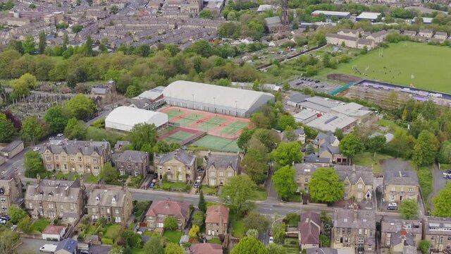 Aerial drone flyover shot of a tennis club and courts in English housing estate