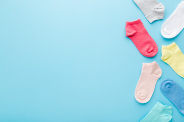 Colorful kid short socks on light blue table background. Pastel color. Closeup. Empty place for...