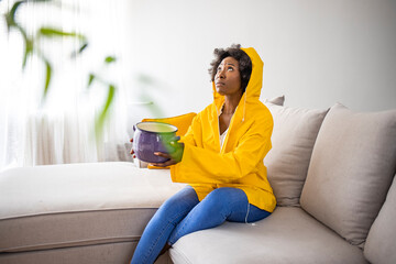 Shocked Woman Looks at the Ceiling While Collecting Water Which Leaks in the Living Room at Home....