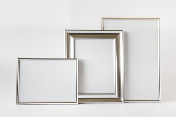 Composition with three silver framed canvas with blank space on white background.