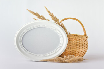 Creative country style composition with wooden basket and white round oval blank frame.