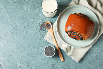 Tasty bun with poppy seeds and glass of milk on color background