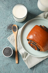 Tasty bun with poppy seeds and glass of milk on color background