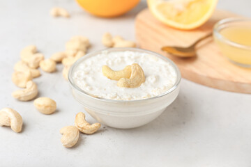 Bowl with cashew sour cream, nuts and lemon juice on light background, closeup