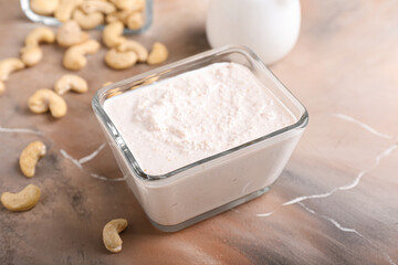 Bowl with cashew sour cream and nuts on grunge background, closeup