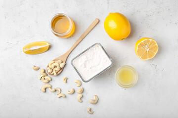 Bowl with cashew sour cream, nuts, honey and lemon juice on light background