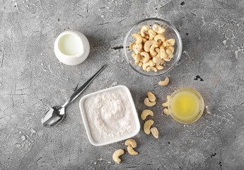 Composition with cashew sour cream, nuts and lemon juice on grey background