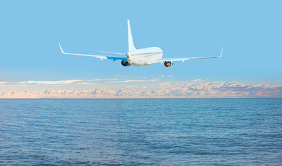 Fototapeta na wymiar White passenger airplane over the clouds - Travel by air transport