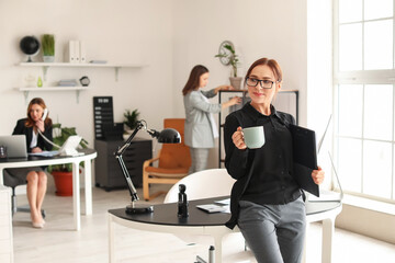 Fototapeta na wymiar Female accountant with cup of coffee in office