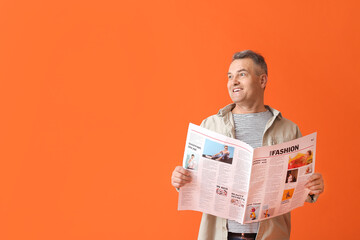Mature man with newspaper on color background