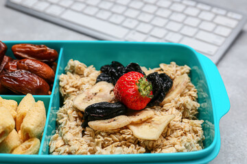 Lunchbox with tasty food and keyboard on light background