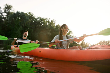Happy young woman and her boyfriend enjoying kayaking together in a lake on a late summer afternoon