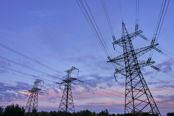 silhouette of high voltage power lines against a colorful sky at sunrise.
