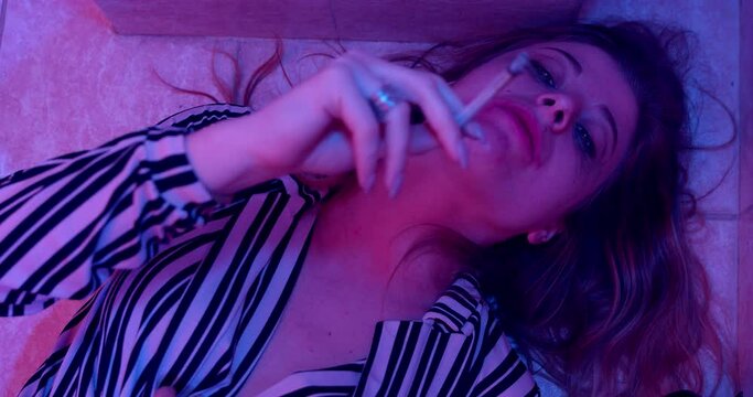 abuse, addiction - dazed woman lying on the floor smokes a joint