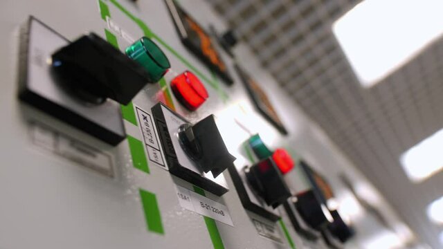 Motion past black plastic levers row on switchgear in light hall of electricity distribution substation close low angle shot