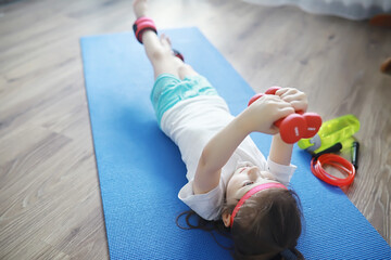 Sport and healthy lifestyle.Child playing sports at home. Yoga mat dumbbell and jump rope. Sports background home exercises concept.
