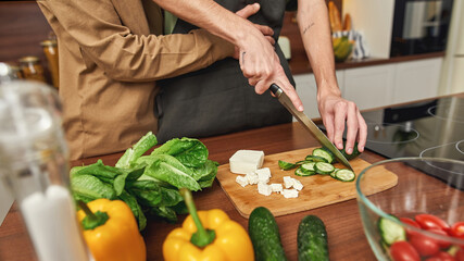 Hugging same-sex male partners cutting cucumber