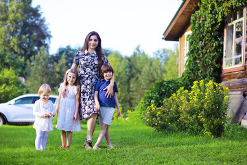 Obraz premium Young large family on a summer morning walk. Beautiful mother with children is playing in the park.