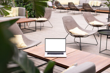 Laptop computer mock up with white blank screen on the table in garden or open air. Relax after work. Fresh air.