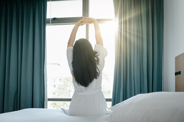 Fototapeta na wymiar Pretty Woman Stretching in Her Bed After Wake Up in The Morning, Young Woman Having Relax During Waking Up on Bedroom. Beautiful Brunette is Waking up and Stretches in Resting Room at Morning