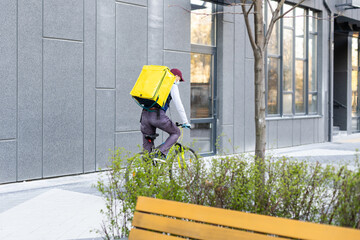 Delivery Man standing with yellow thermo backpack for food delivery near the entrance home with empty space to copy paste
