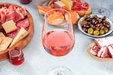 Rose wine and Italian antipasti or Spanish tapas in a bar. Blue cheese, prosciutto di Parma ham, jamon, olives and salmon sandwiches. Gourmet appetizers